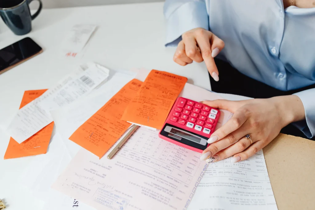 A woman focused on a calculator, calculating her payment amount with a thoughtful expression.