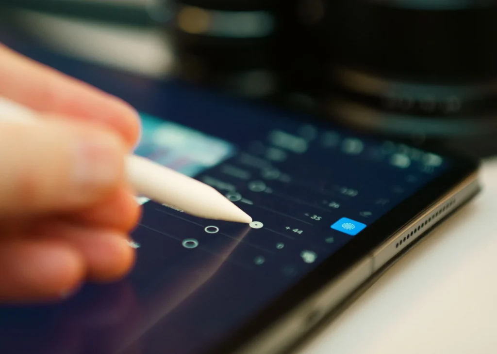 A person holding a pen above a tablet screen, preparing to write or draw on the digital surface.